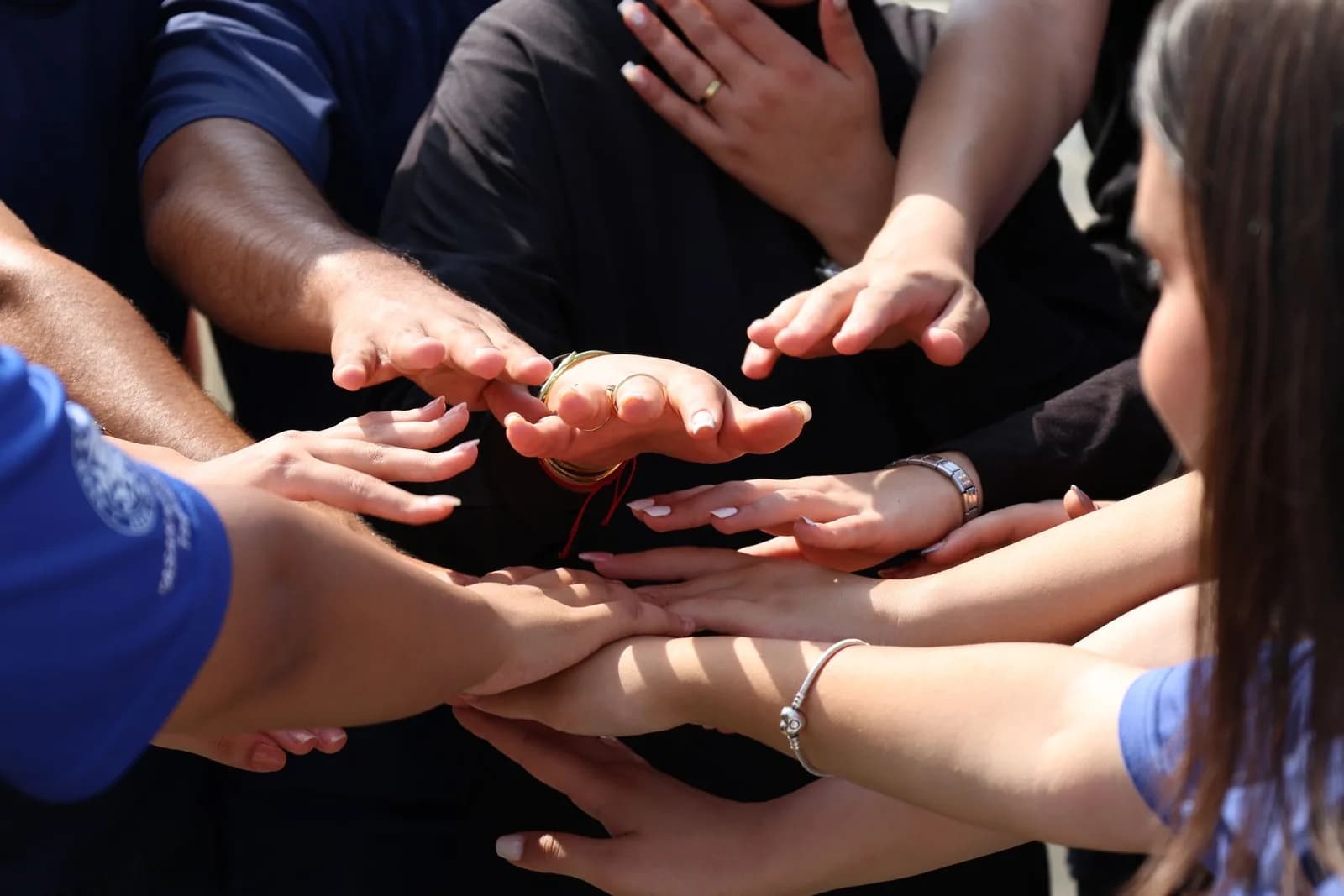 A diverse group joining hands in a circle to show unity and support.